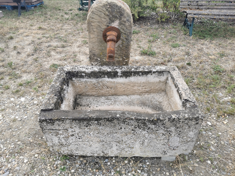 kleiner quadratischer Brunnen mit Pumpenstock
